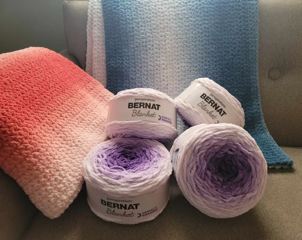 Bernat Perfect Phasing Yarn finished blankets in red and blue, and purple skeins.