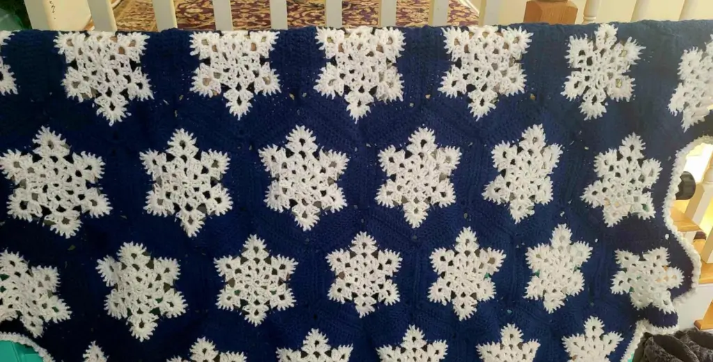 PIcture of a blue blanket with white snowflake granny squares