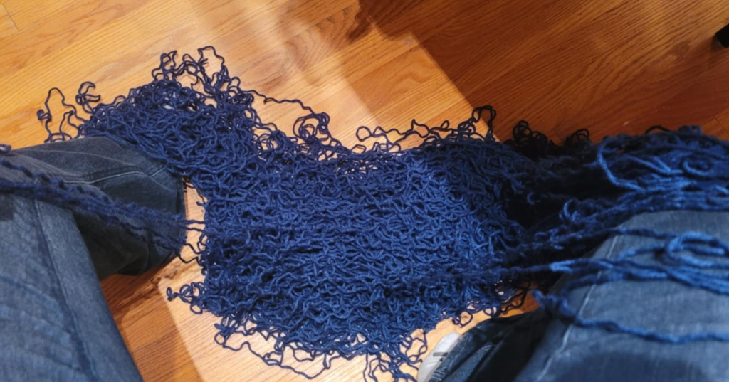 blue frogged yarn in a a messy pile on a wooden floor