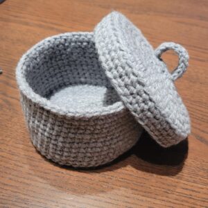 Crocheted tabletop scrap yarn bin with matching lid in gray color worsted weight yarn.