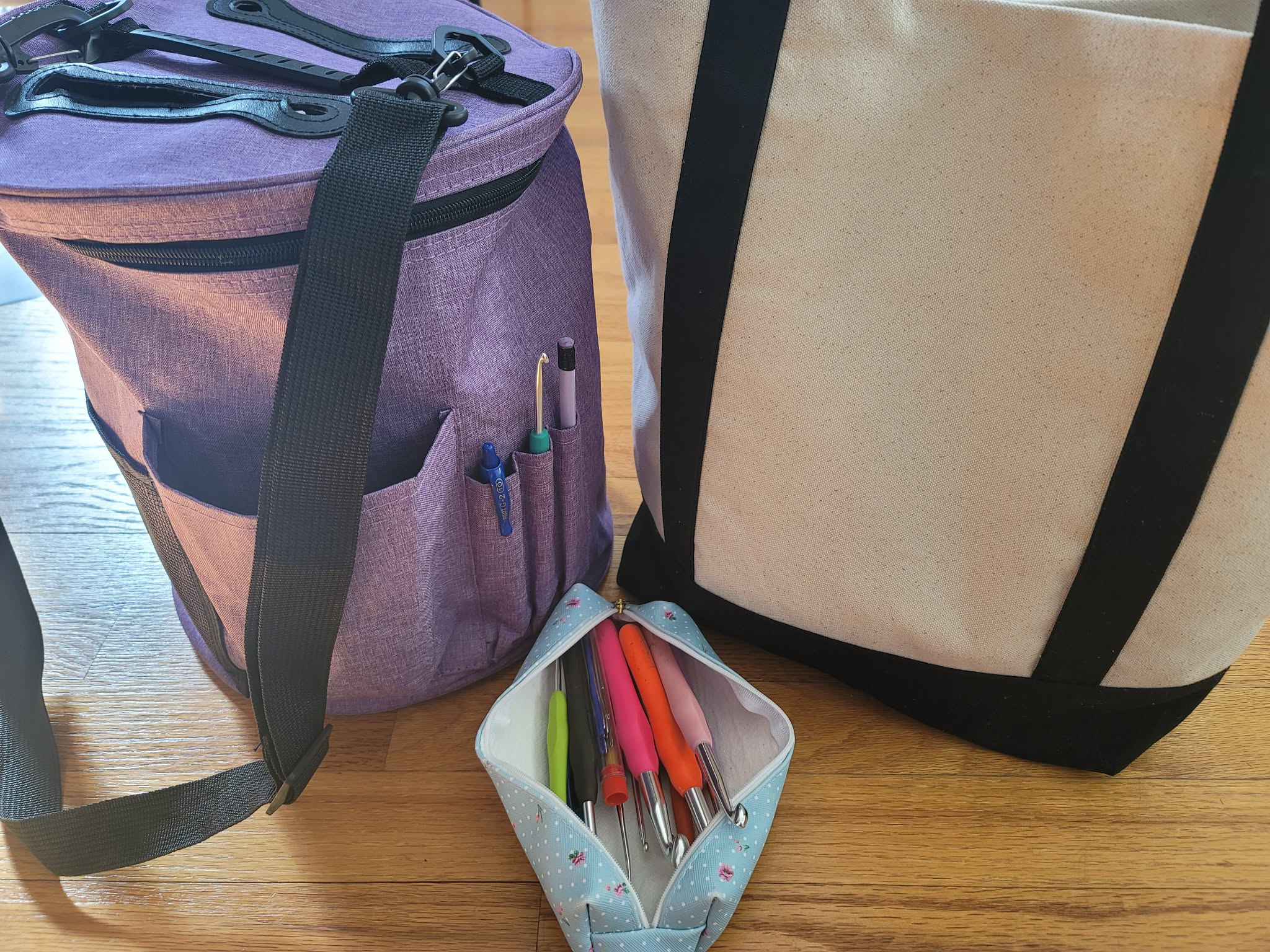 Purple zippered crochet bag with storage pockets, a single teacher-type bag, and a crochet hook pouch