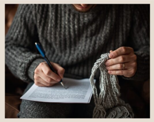 Picture of a man writing with a pen using his right hand and hold yarn in his left hand.